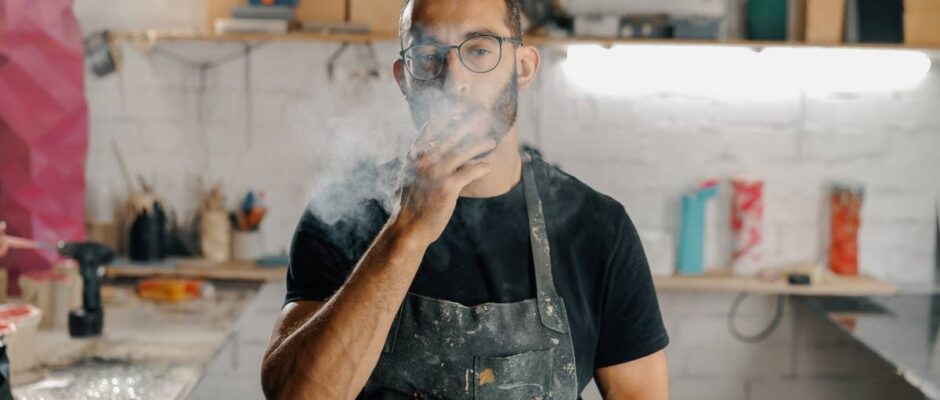 Male artist sculptor artisan smokes cigarette in the workshop.